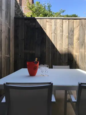 a white table with wine glasses on it with a fence at Gezellig stadshuisje met patio. in Tongeren