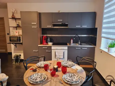 a kitchen with a wooden table and chairs in a kitchen at La suite de lati in Liège