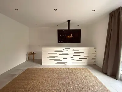 a living room with a white wall and a rug at Casa Honey in Liège