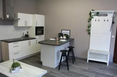 a kitchen with white cabinets and a counter with stools at Elena's Apartment in Liège