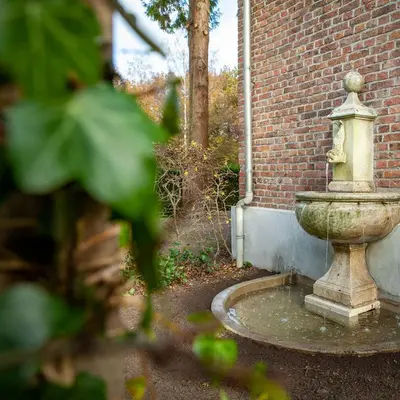 a stone fountain in front of a brick building at Villa Asch in As
