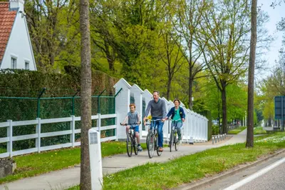 two adults and a child riding bikes down a sidewalk at EuroParcs Hoge Kempen in Zutendaal