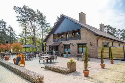 a building with tables and chairs in front of it at EuroParcs Hoge Kempen in Zutendaal