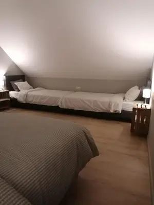 two beds in a room with white walls and wood floors at Het Innerhof in Oudsbergen