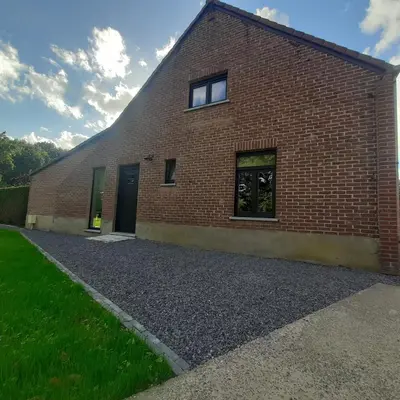 a brick building with two doors and a gravel driveway at Het Innerhof in Oudsbergen