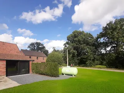 a garden with a water tank in the grass at Het Innerhof in Oudsbergen