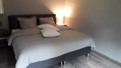 a bedroom with a large bed with white sheets and pillows at Het Innerhof in Oudsbergen