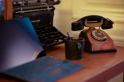 a telephone and a cup on a desk with a laptop at GITADIN - Deluxe Suite Valens - Historical Center in Liège
