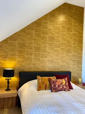 a bedroom with a bed with a wooden wall at Le Clos du Verger in Aubel
