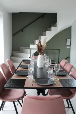a dining room with a black table and pink chairs at Aan Wal in Rekem