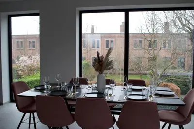 a dining room with a table and chairs and windows at Aan Wal in Rekem