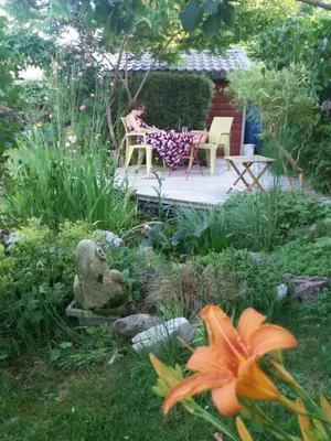 a woman sitting in a chair in a garden at L'Atelier Bed and Breakfast in Andrimont