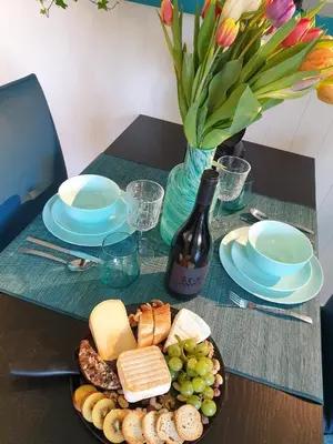 a table with a plate of cheese and grapes and a bottle of wine at Tijd voor jezelf en elkaar bij Me&We in Zutendaal