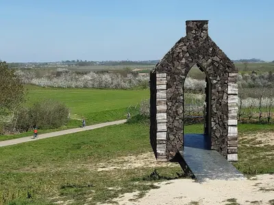 a stone archway in a field next to a road at Aan het Singelhof - Mirabelle -- 4 sterren -- met sunshower en tuin in Sint-Truiden