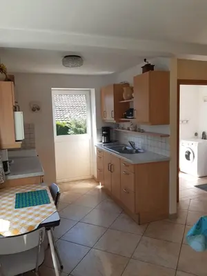 a kitchen with wooden cabinets and a table and a door at Aan het Singelhof - Mirabelle -- 4 sterren -- met sunshower en tuin in Sint-Truiden