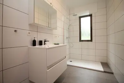 a white bathroom with a sink and a shower at Oscappart in Eupen