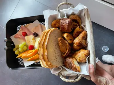 a tray of food with a basket of bread and pastries at Guest House en famille ou en couple à la campagne in Romsée