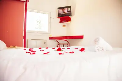 a white bed with red flowers on it at Class'eco Liège in Liège