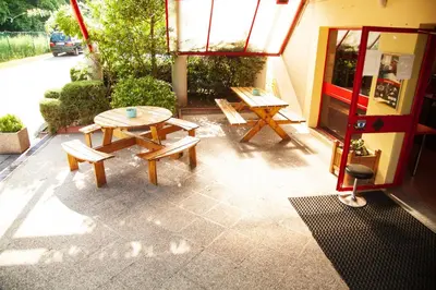 a patio with benches and a table and a window at Class'eco Liège in Liège