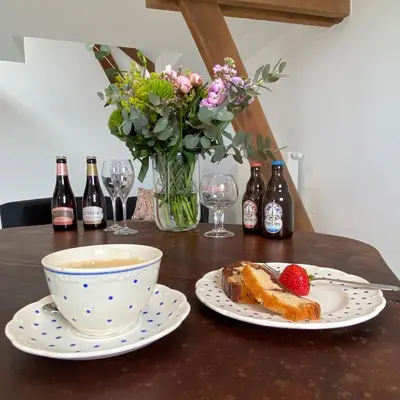 a table with a bowl of coffee and a plate of food at Ô Macra B&B - Aubel, Pays de Herve in Aubel