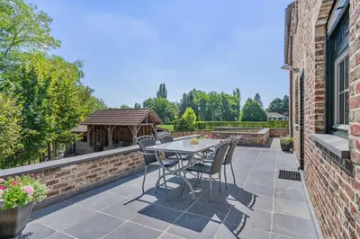 a patio with a table and chairs and a gazebo at Huize Koedoe in Tongeren