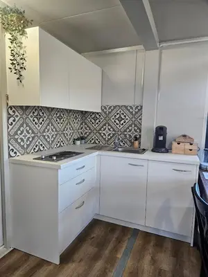a kitchen with white cabinets and a counter top at Houten huisje tussen paarden in Nieuwerkerken
