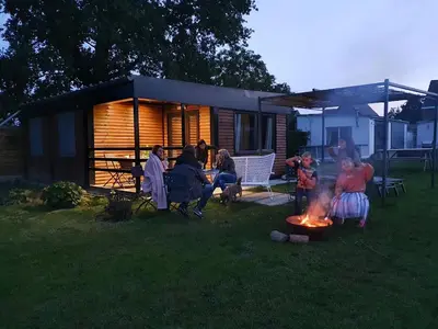a group of people sitting around a fire in a yard at Houten huisje tussen paarden in Nieuwerkerken