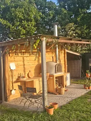 an outdoor kitchen with a table and chairs in a backyard at Houten huisje tussen paarden in Nieuwerkerken