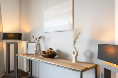 a room with a table with a vase on it at Saint Pablo Design Apt I 2BR, Free Parking, Stunning View & Large Terrace in Hasselt