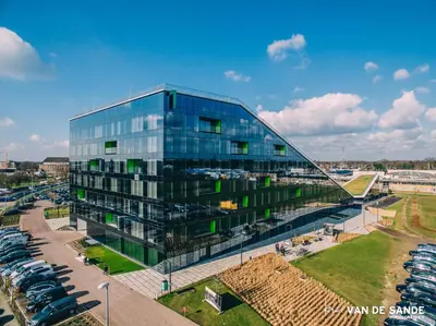 a glass building with cars parked in a parking lot at Saint Pablo Design Apt I 2BR, Free Parking, Stunning View & Large Terrace in Hasselt