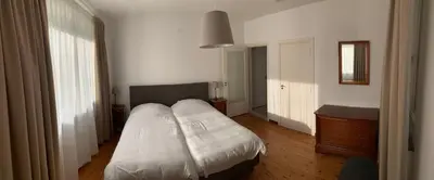 a bedroom with a white bed and a wooden floor at De Lelie in Achel