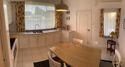 a kitchen with a wooden table and chairs in it at De Lelie in Achel