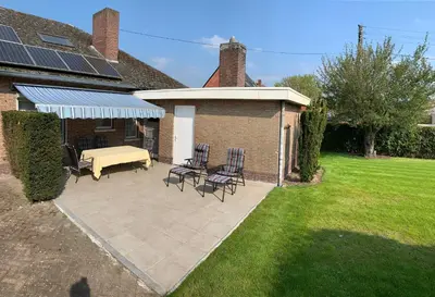 a patio with a table and chairs and a house at De Lelie in Achel