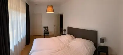 a bedroom with a bed with a white blanket at De Lelie in Achel