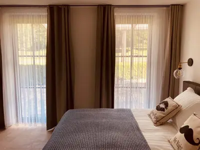 a bedroom with a bed and two large windows at De Molenhoeve B&B in Voeren