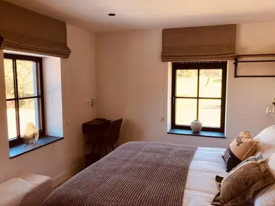 a bedroom with a bed and two windows at De Molenhoeve B&B in Voeren