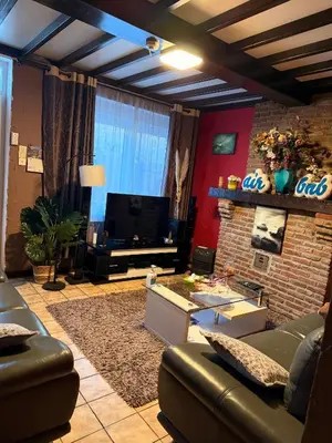 a living room with a couch and a television at Bien-être-Au-calme et parking gratuit in Seraing