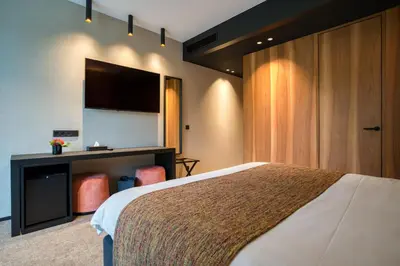 a hotel room with a bed and a flat screen tv at Aux Etangs - Hôtel in Battice