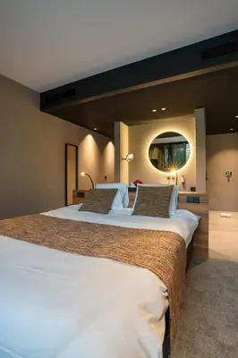 a large bedroom with two beds and a mirror at Aux Etangs - Hôtel in Battice