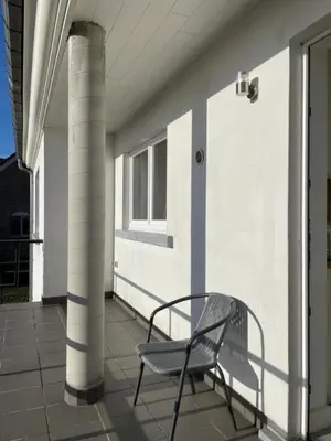 a bench sitting on a porch next to a building at Het Damhert in Kortenaken