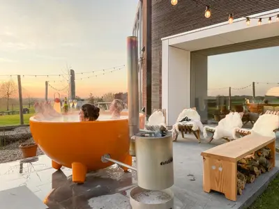 an orange bath tub with a man in it at Huis van Hout - architectenwoning met grote panorama tuin - design hot tub optioneel in Herk-de-Stad