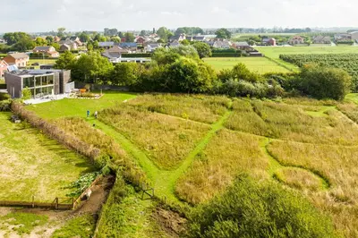 a field of hay with a town in the background at Huis van Hout - architectenwoning met grote panorama tuin - design hot tub optioneel in Herk-de-Stad