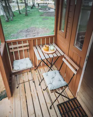 a porch with two chairs and a table with a plate of food at Glamping Limburg - nabij Nationaal Park Hoge Kempen in Kinrooi