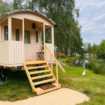 a small house with a staircase next to a river at Glamping Limburg - nabij Nationaal Park Hoge Kempen in Kinrooi