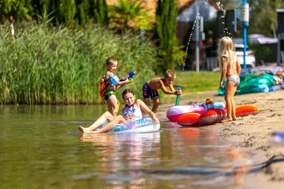 a group of children playing in the water at the beach at Glamping Limburg - nabij Nationaal Park Hoge Kempen in Kinrooi