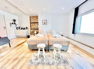 a bedroom with a bed and two stools at Logies by Suzan in Hasselt