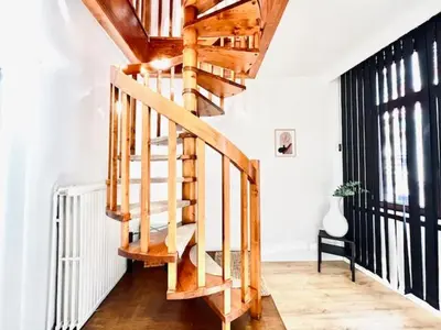 a wooden spiral staircase in a room with a window at Logies by Suzan in Hasselt