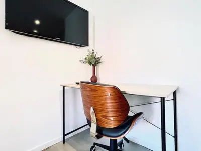 a wooden chair sitting in front of a desk with a television at Logies by Suzan in Hasselt