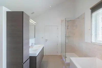a white bathroom with a shower and a sink at Ruime woning met grote omheinde tuin in Hasselt