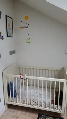 a white crib in a room with a wall at Ruime woning met grote omheinde tuin in Hasselt